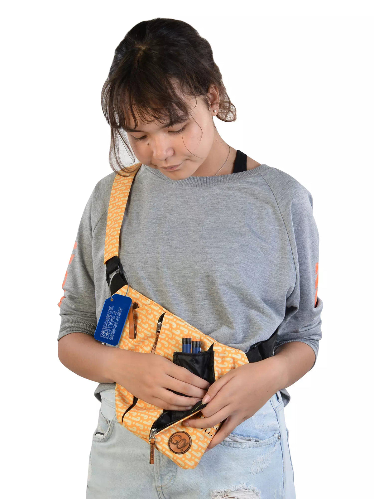 Person holding a yellow shoulder bag with a blue 'Diabetic Type 1 Insulin Dependent' luggage tag attached.