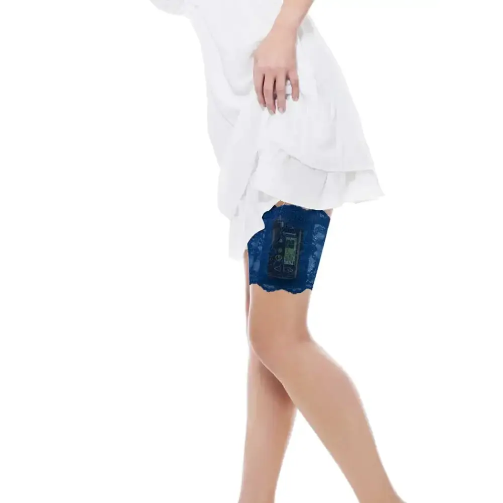 Woman wearing blue lace garter for insulin pump under white dress lifting hem to show device holder