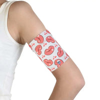 Protective armband with pink heart design securing glucose sensor on teenager's upper arm.